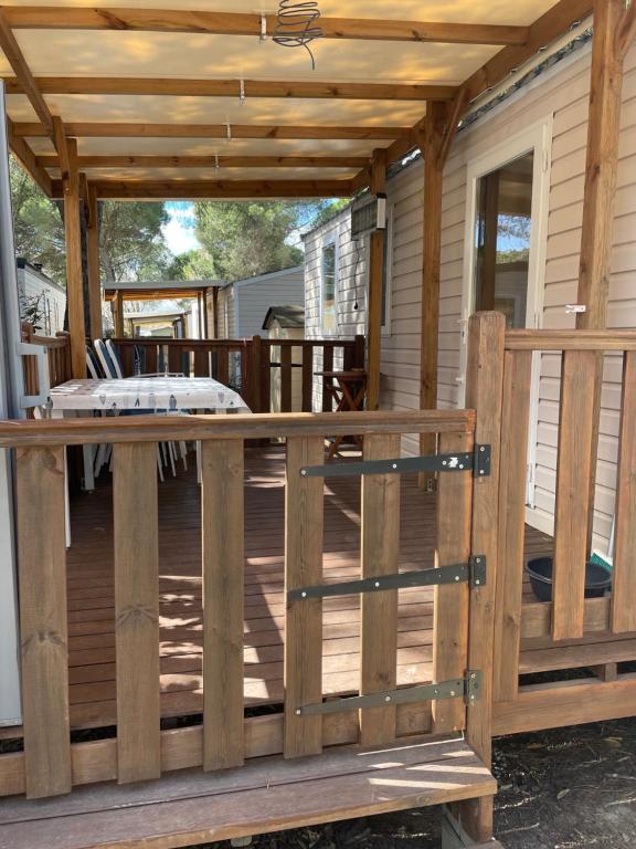 eine Holzterrasse mit einer Pergola auf einem Haus in der Unterkunft Mobil home 8 personnes camping l elysee in Le Grau-du-Roi