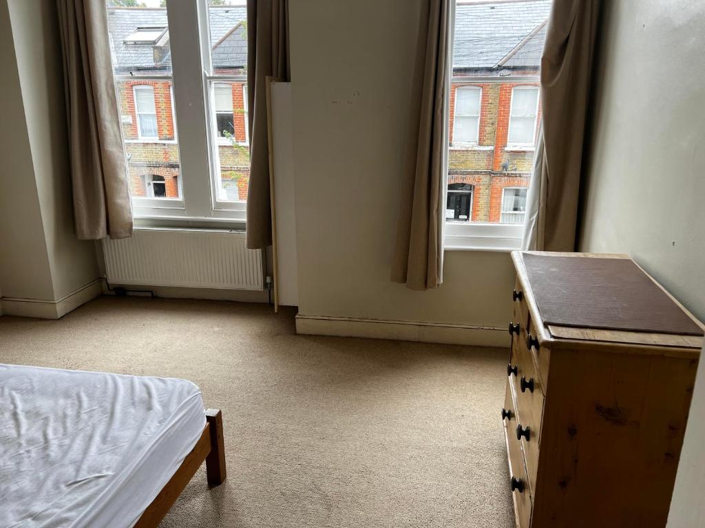 1 dormitorio con 2 ventanas, 1 cama y 1 mesa en 16 Beverstone road en Londres