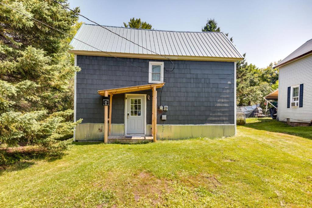 une maison grise avec une porte et une cour dans l'établissement Pet-Friendly Michigan Getaway with Porch and Kayaks!, à Ontonagon