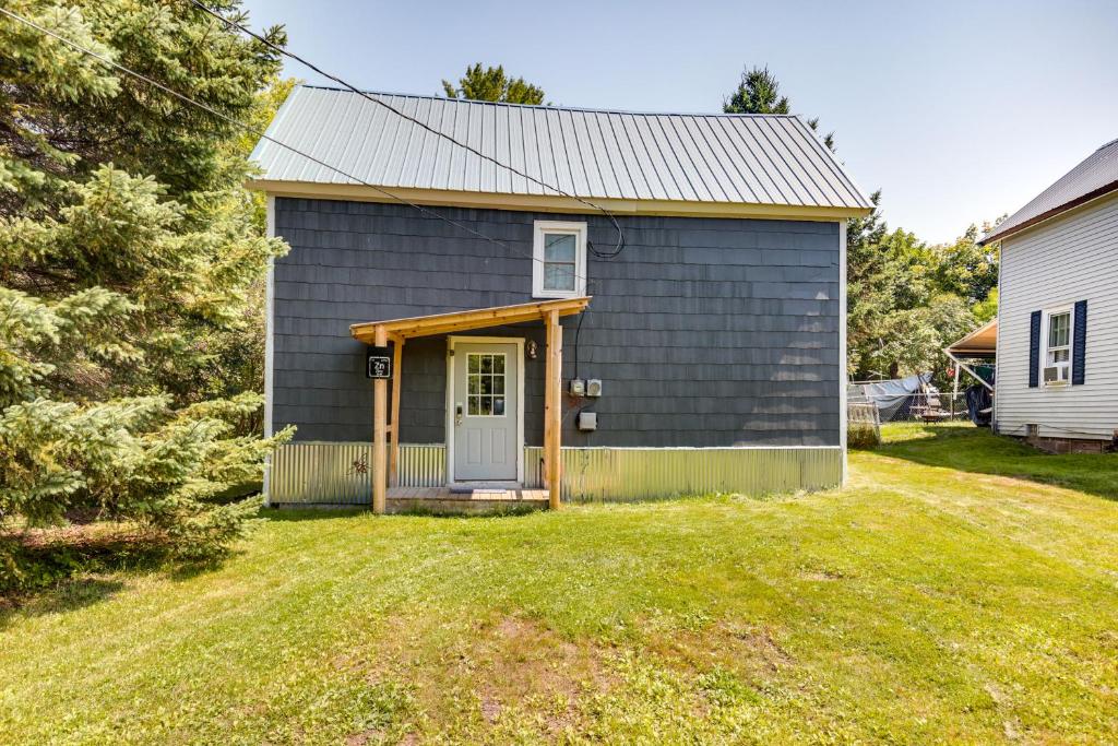 a gray house with a door and a yard at Pet-Friendly Michigan Getaway with Porch and Kayaks! in Ontonagon