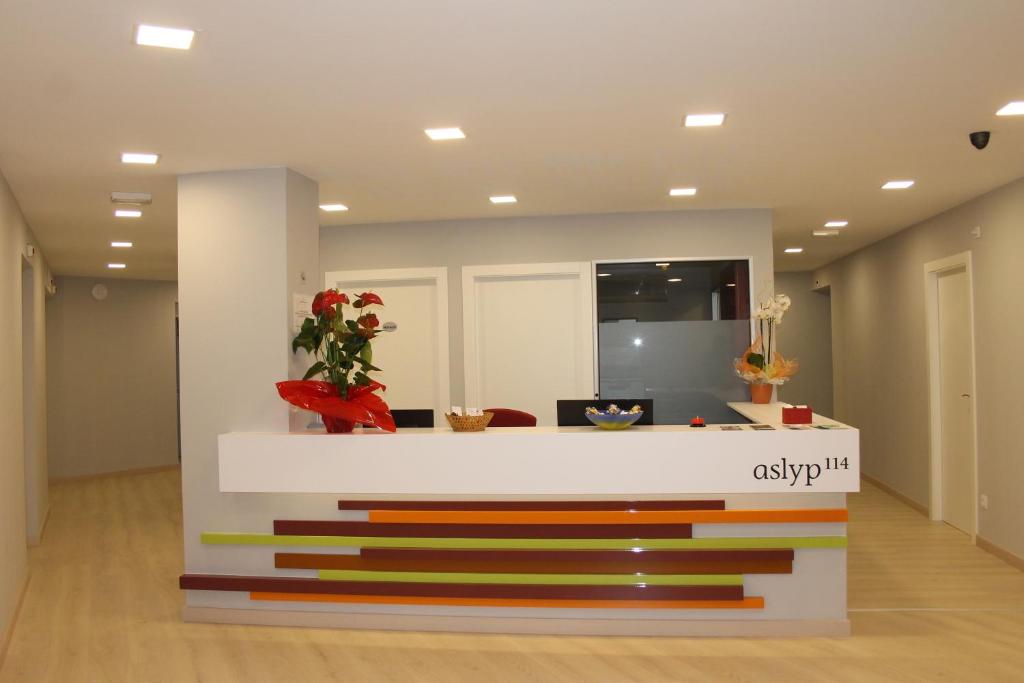 vestíbulo con recepción y escaleras coloridas en Hostal Aslyp 114, en Barcelona