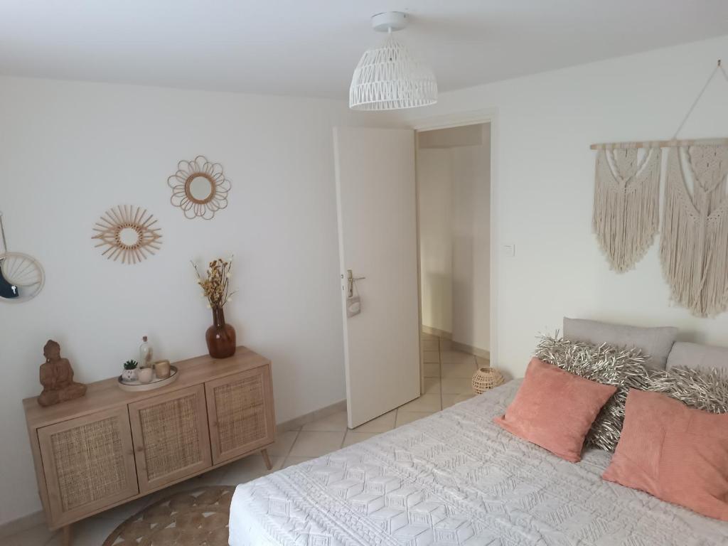 a bedroom with a white bed with pink pillows at Havre de paix Les pélicans in Vichy