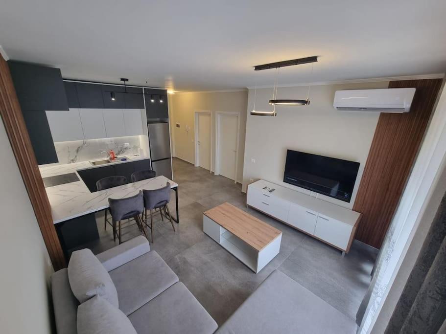 een woonkamer met een bank en een tafel en een keuken bij H&E Sea view 2-Bedroom Apt Qerret in Golem