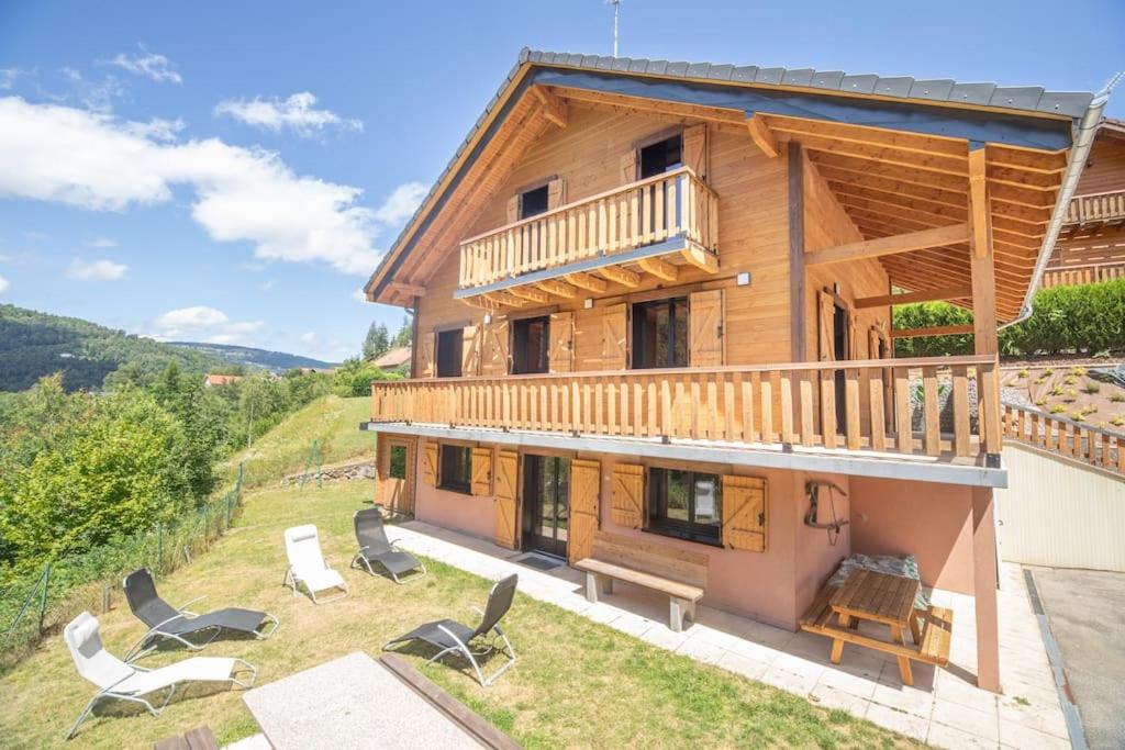 Cette grande maison en bois dispose d'un balcon et de chaises. dans l'établissement Les Marmottes, 10 à 20p avec bb-foot, billard, bar, à Cornimont