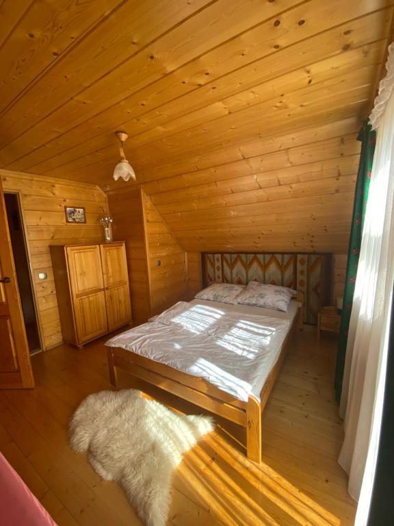 ノヴィ・タルクにあるDomek w górachの木造キャビン内のベッド1台が備わるベッドルーム1室を利用します。
