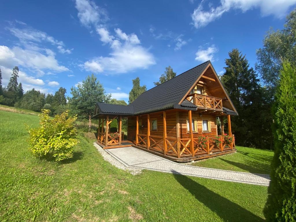 una cabaña de madera en un campo con un patio verde en Domek w górach en Nowy Targ