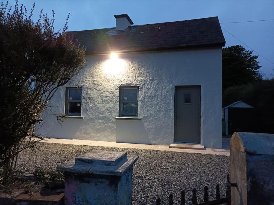 a white house with a light on the side of it at Fox's Cottage in Millstreet