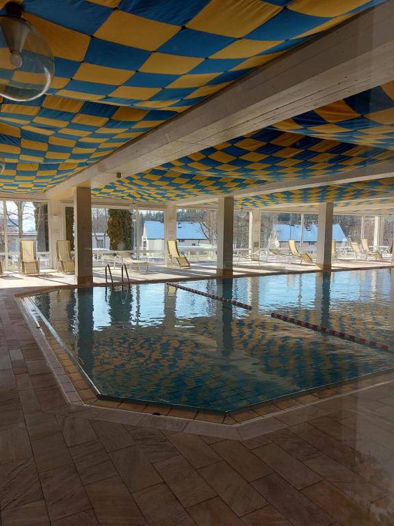 a large swimming pool with a blue and yellow ceiling at Kuschelig im Allgäu in Scheidegg