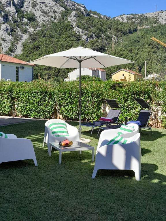 a group of chairs and an umbrella on the grass at Apartment Emmi in Omiš