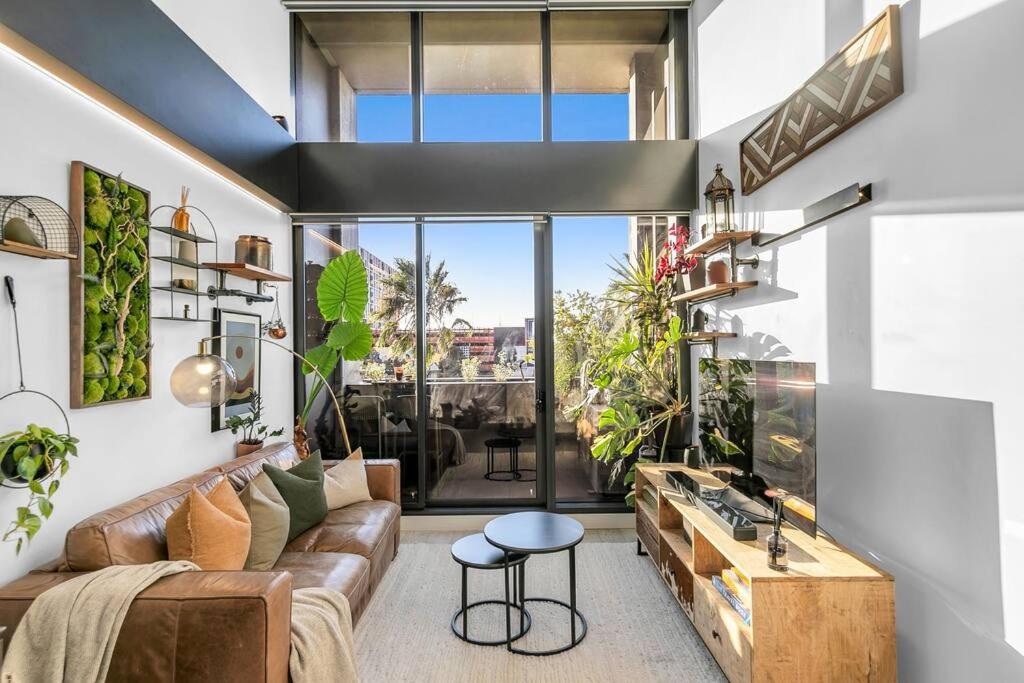 a living room with a couch and some plants at Sol Docklands - Unique 3 Bedroom Loft, Infinity Pool, Gym, Free Parking and Free Trams in Melbourne