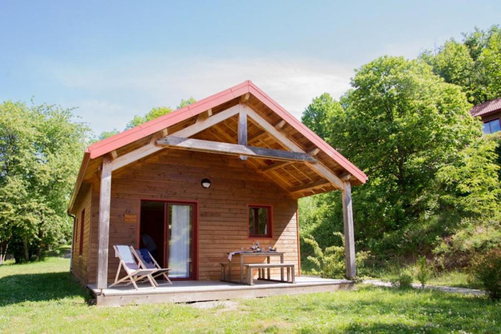 une petite cabane en rondins avec une terrasse couverte et 2 chaises dans l'établissement Les Châtaigniers du Lac, à Pourcharesses