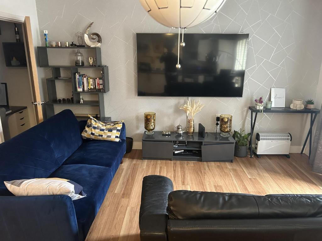 a living room with a blue couch and a flat screen tv at Immaculate 2-Bed Apartment in Romford in Romford