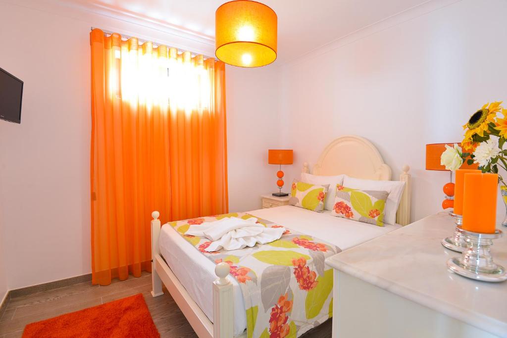 a small bedroom with a bed with an orange curtain at Holidays Nazaré Centro in Nazaré