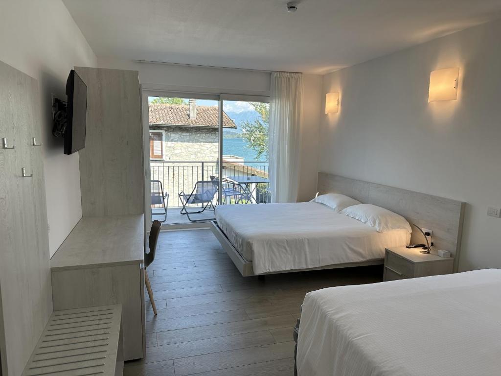 a hotel room with two beds and a balcony at Resort le Vele Suites and Apartments in Domaso