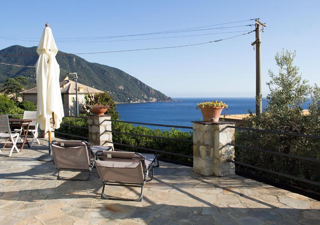 a patio with chairs and an umbrella and the ocean at La CONCHIGLIA Bed & Breakfast in Camogli