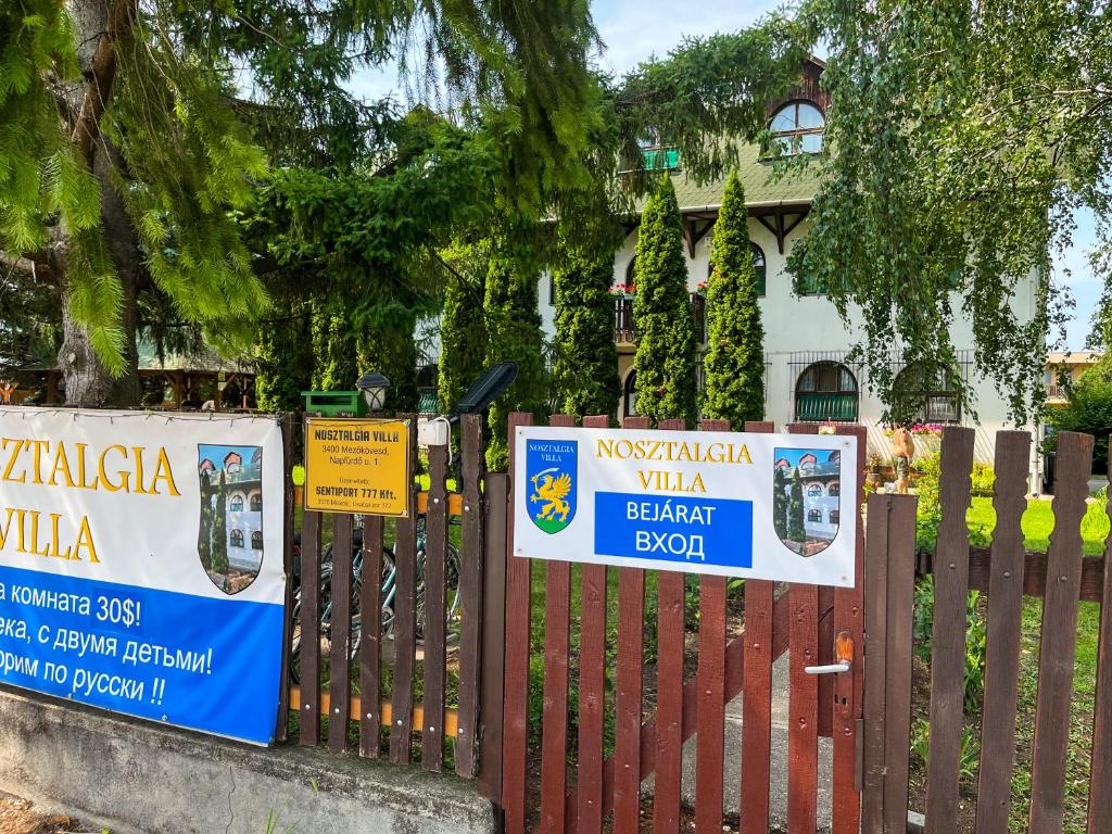 una valla con carteles delante de una casa en Nosztalgia Villa, en Mezőkövesd