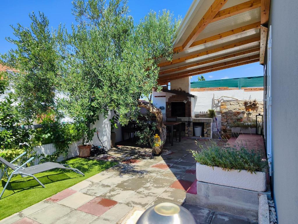 einen Hinterhof mit einer Terrasse mit einem Tisch und einem Baum in der Unterkunft Mobile house Green garden in Murter