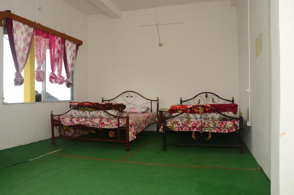 2 camas en una habitación con suelo verde en Everett Hut, en Darjeeling