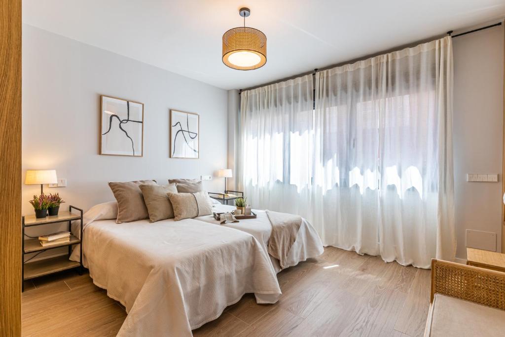 a white bedroom with a bed and a large window at AQUI en Madrid in Madrid