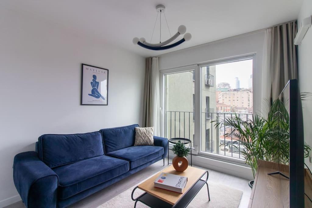 Sofá azul en la sala de estar con ventana en Newly Built Bright 2BR w Free Shuttle #68, en Estambul
