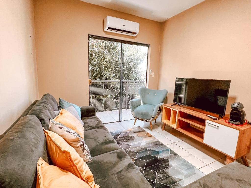 Una sala de estar con un sofá y un televisor de pantalla plana. en Amplio loft en zona residencial de Asunción, en Asunción