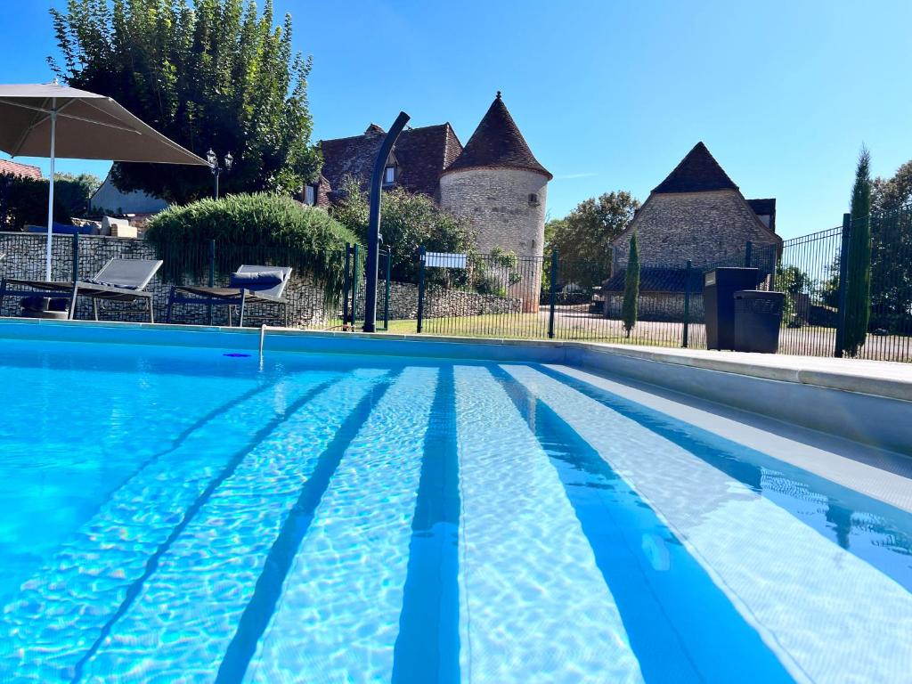 a swimming pool in front of a house at Hôtel Les Vieilles Tours Rocamadour in Rocamadour