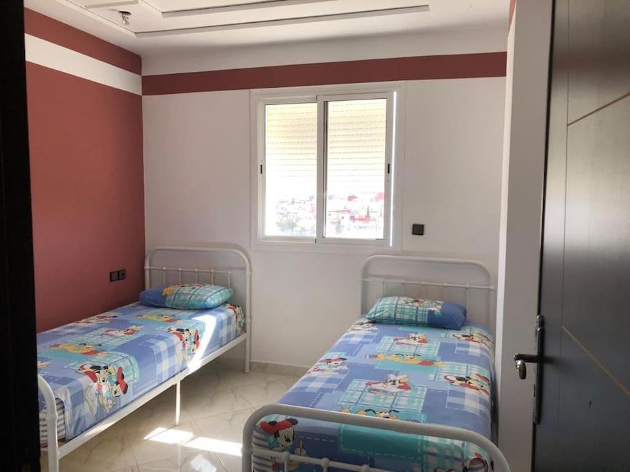 two beds in a room with red and white walls at Logement entier : appartement in Larache