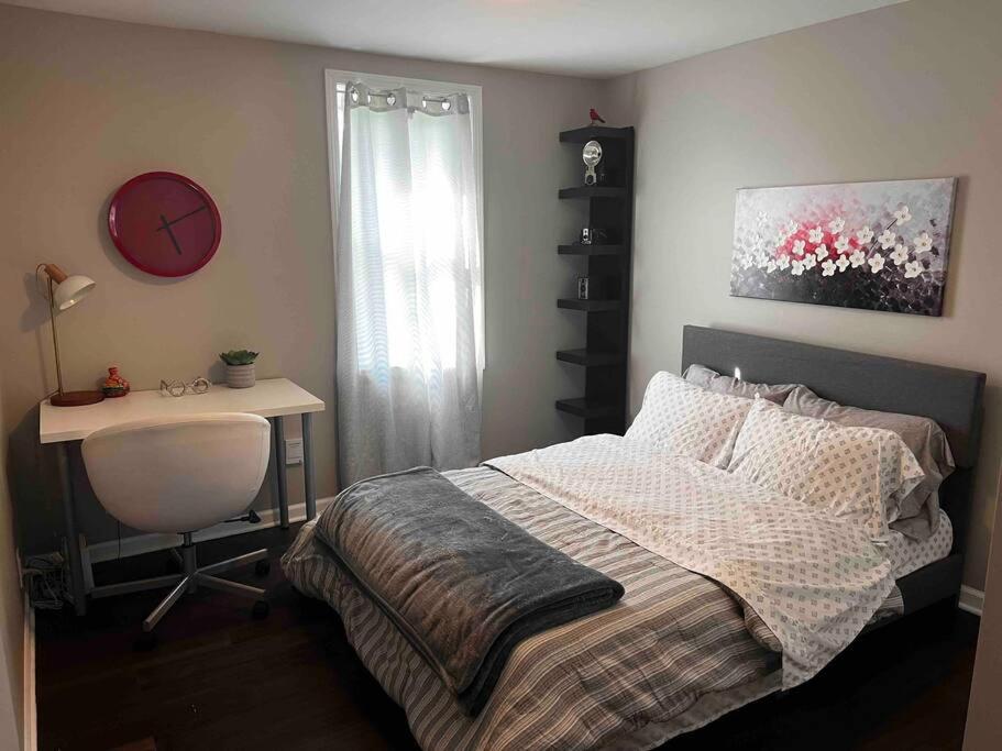 ein Schlafzimmer mit einem Bett, einem Schreibtisch und einer Uhr in der Unterkunft Perfect little paradise in Geneva