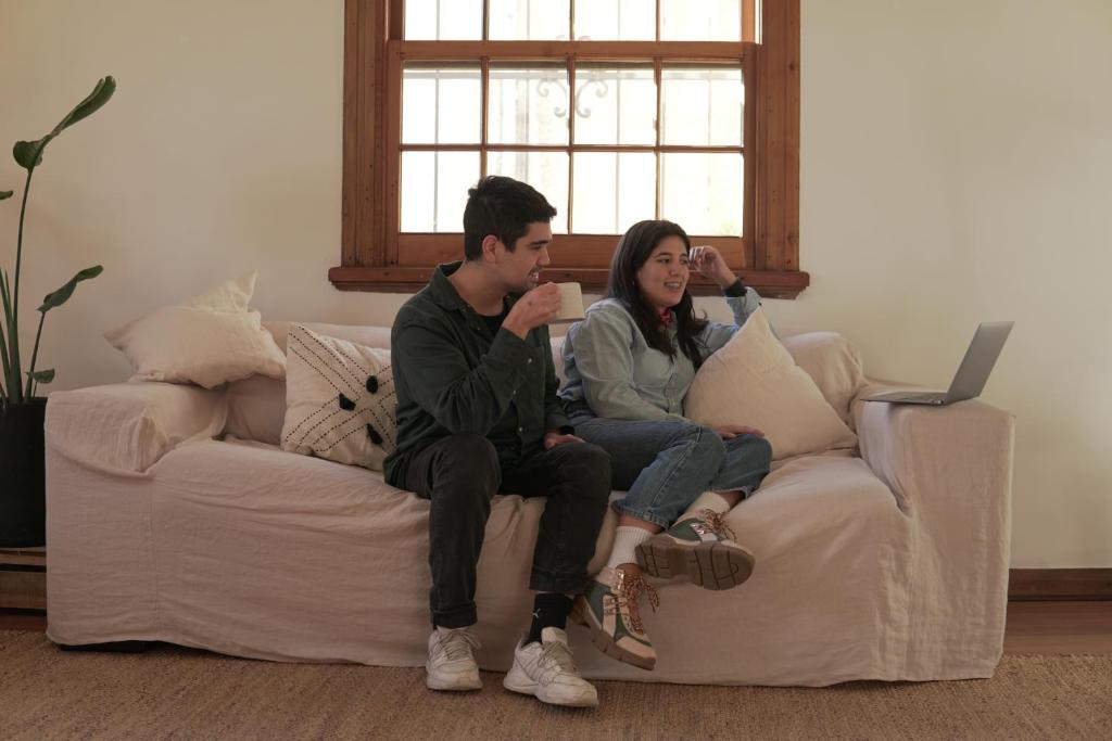 a man and a woman sitting on a couch at La Posada Coliving in Viña del Mar