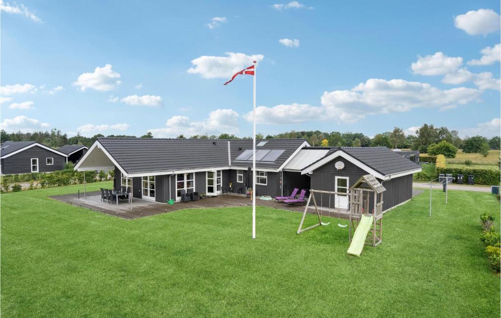 ein Haus mit einem Spielplatz und einer Flagge im Hof in der Unterkunft 4 Bedroom Cozy Home In Hadsund in Hadsund