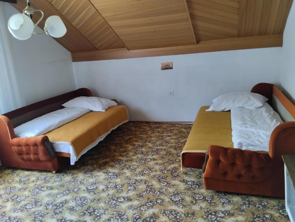 2 Betten in einem kleinen Zimmer mit Sofa in der Unterkunft Smeštaj Milekić - Nova Varoš in Vraneša