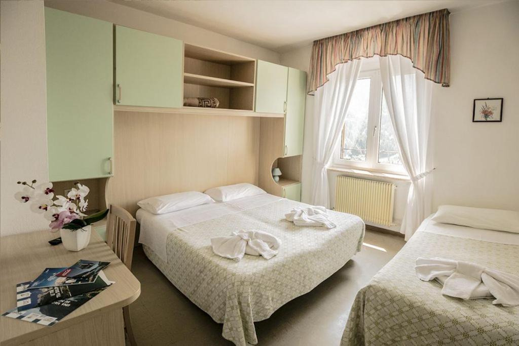a hotel room with two beds and a window at Hotel Aurora in Molveno
