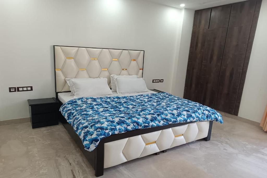 a bedroom with a large bed with a blue and white blanket at Mintstar Apartment and Suites, East of Kailash in New Delhi