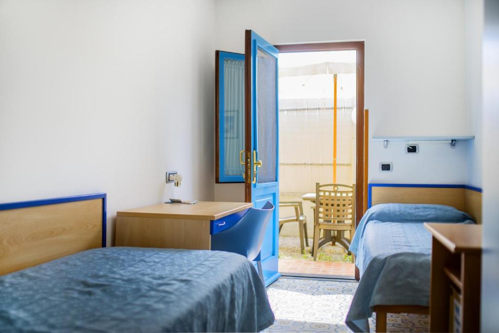a bedroom with two beds and a desk and a door at La Capannina in Procida