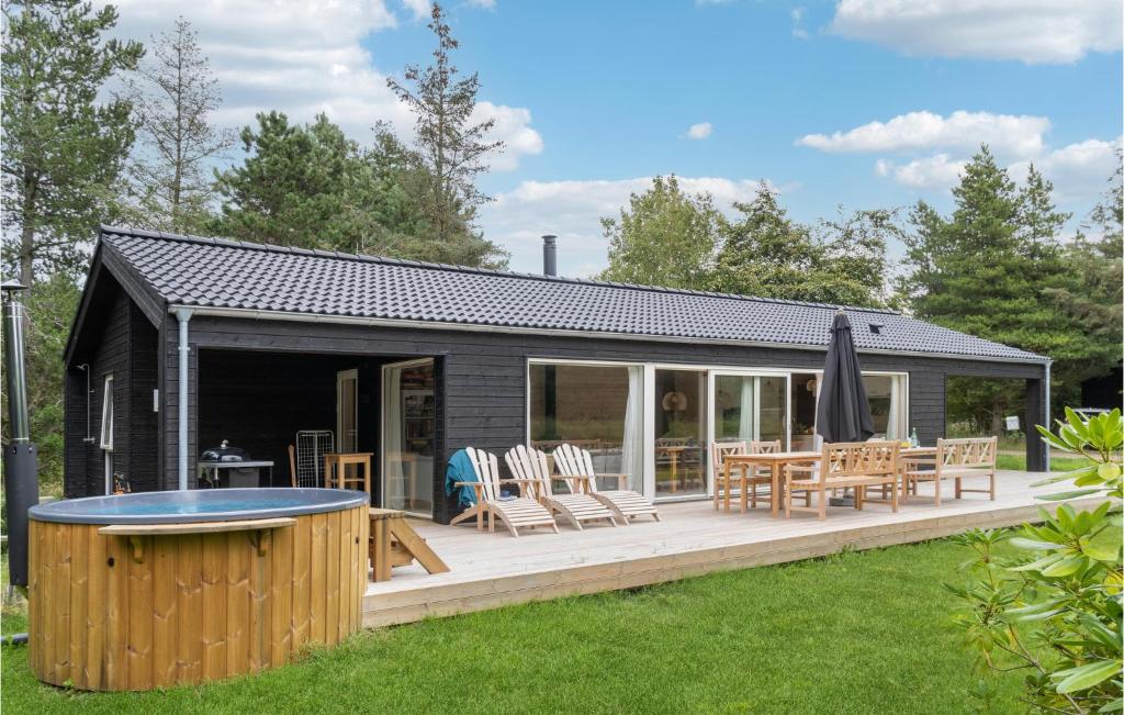 a black cottage with a deck with a table and chairs at 4 Bedroom Nice Home In Hjby in Højby