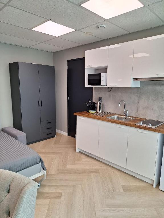 a kitchen with white cabinets and a sink in a room at Mooie studio 14 C in center in Rotterdam
