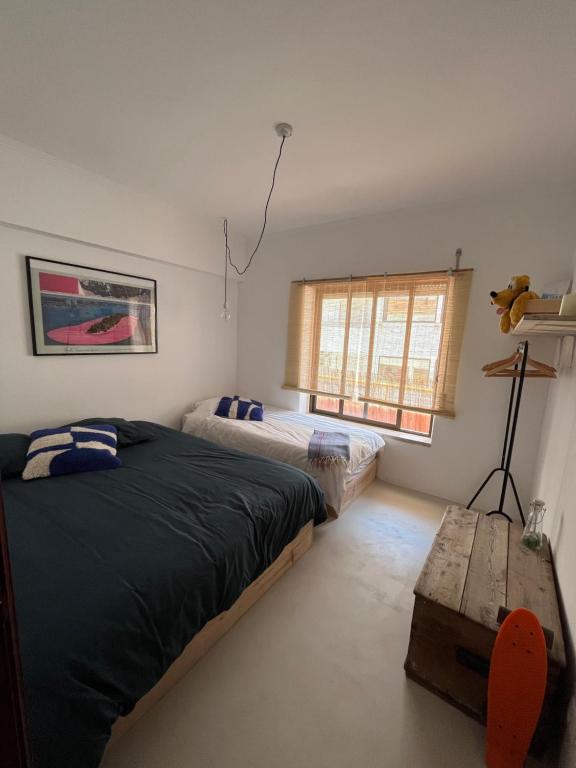een slaapkamer met 2 bedden, een tafel en een raam bij Appartement à 5 min de la plage in Aroeira