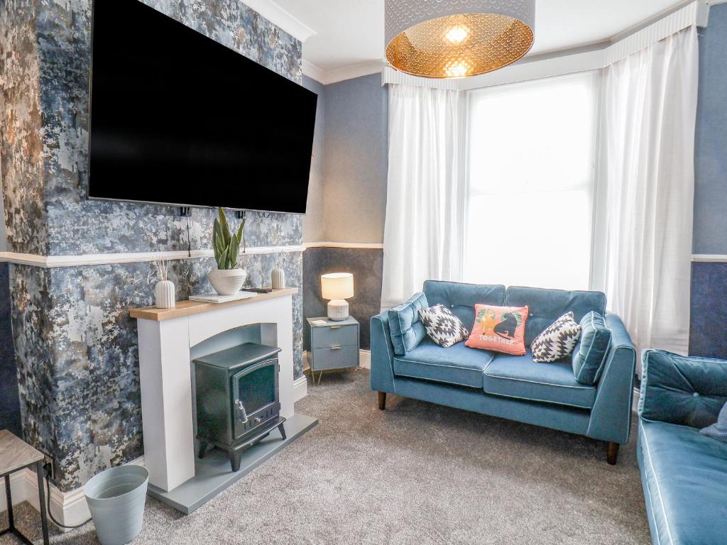 a living room with a blue couch and a tv at 3 Auborough Street in Scarborough