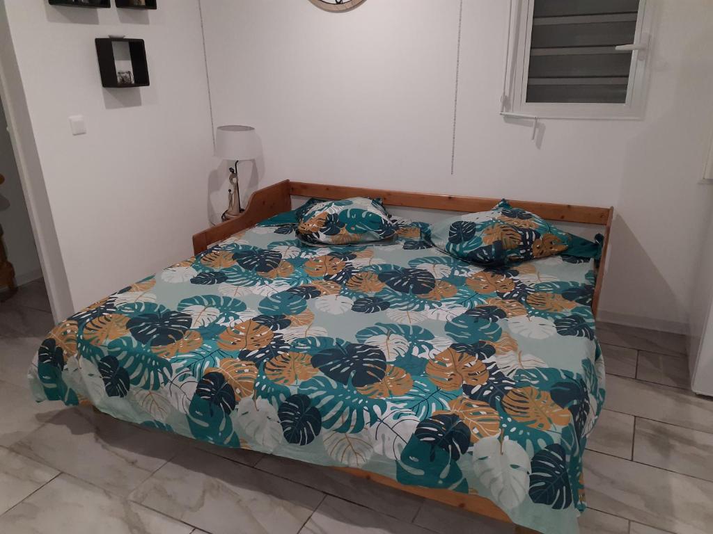 uma cama com um edredão colorido num quarto em Bungalow agéable et confortable, parking securisé em Vieux-Habitants