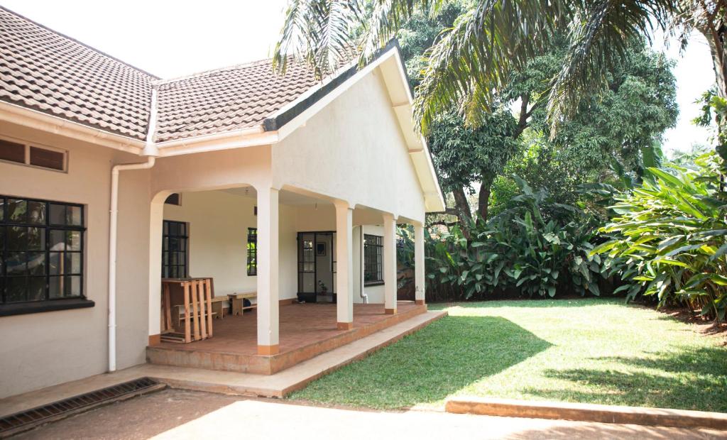 ein Haus mit einer Veranda und einer Liegewiese in der Unterkunft JINJA HOUSE in Jinja