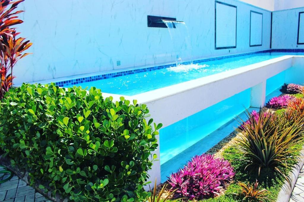 a swimming pool with a fountain and some plants at Villa dos Diamantes - 14 in Porto Seguro