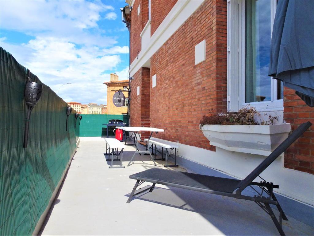 un patio avec une table et des chaises sur un bâtiment dans l'établissement Le Bout du Pont - 5 min à pied de la gare Villebourbon et de l'hypercentre - Vue sur Pont Vieux - Grande terrasse - 8 couchages - 3 chambres spacieuses - 4 lits - Places de stationnement gratuites au pied de l'immeuble, à Montauban