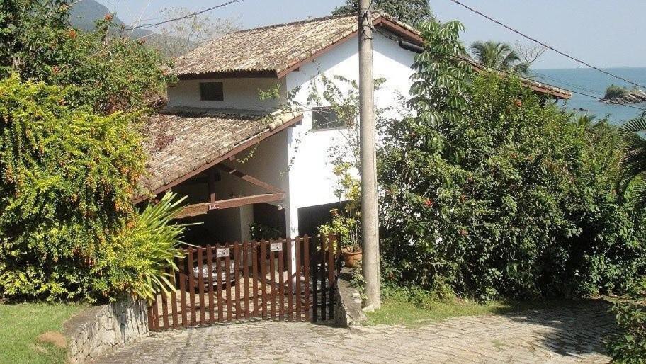 una piccola casa bianca con una recinzione davanti di Linda Costeira na Praia do Julião-Ilhabela a Ilhabela
