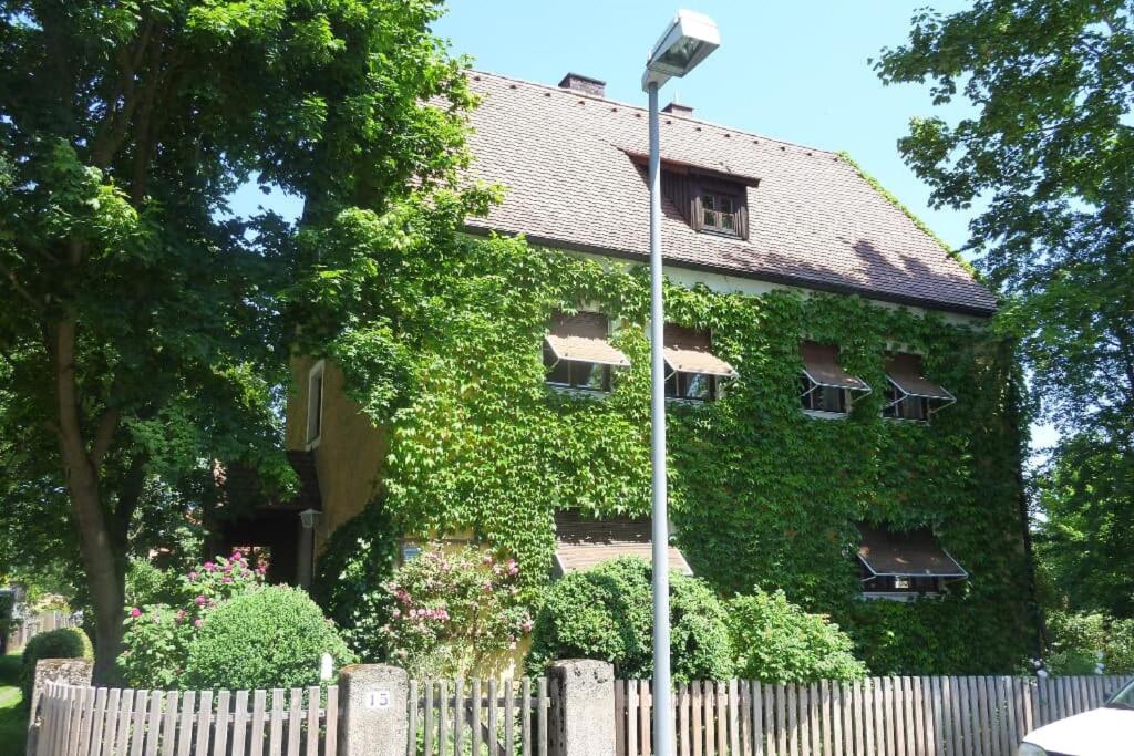 un edificio cubierto de hiedra con una valla blanca en Ferienwohnung Beim Bienagassl en Waldsassen