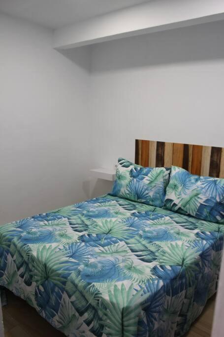 a bed with blue and green sheets and pillows at Alojamiento Teja in Arcos de la Frontera