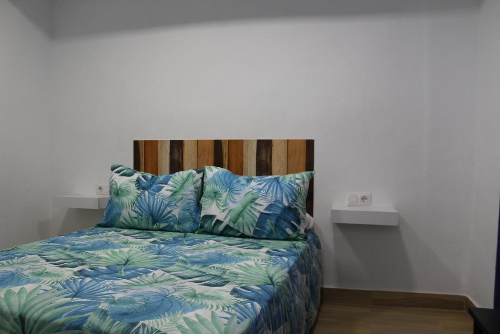 1 cama con edredón azul y 2 almohadas en Alojamiento Teja, en Arcos de la Frontera