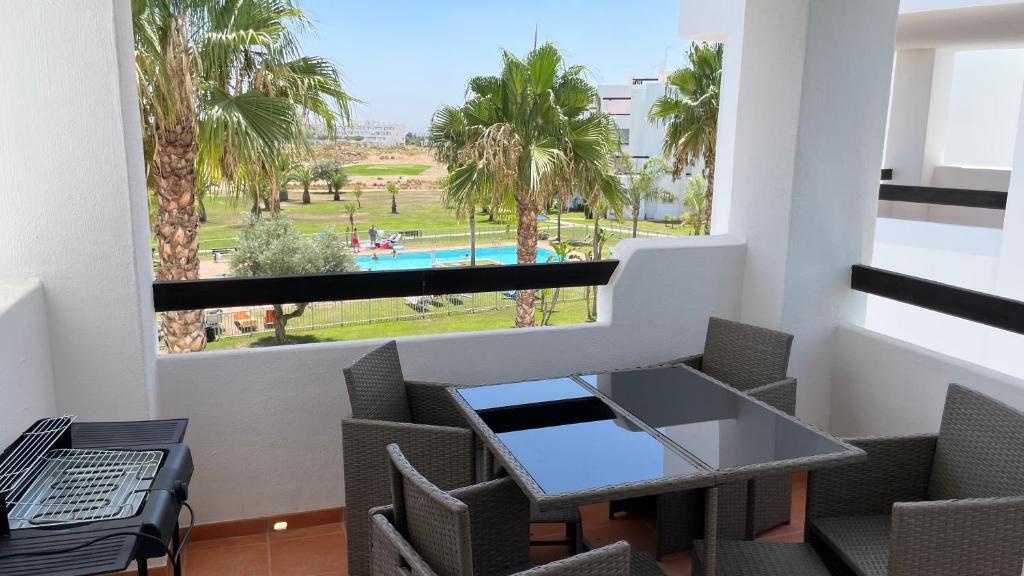 balcón con mesa, sillas y vistas a la piscina en Apartamento golf-resort murcia, en Murcia