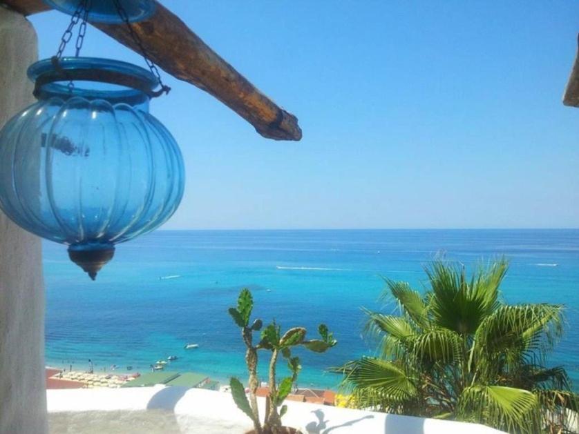 a blue vase hanging from a building with a view of the ocean at Lisca Bianca Tropea in Tropea