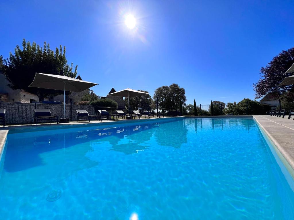 una gran piscina azul con sillas y sombrillas en Hôtel Les Vieilles Tours Rocamadour, en Rocamadour