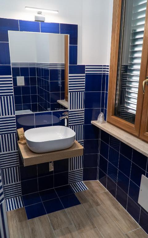 a blue tiled bathroom with a sink and a mirror at Mareterè in Vietri sul Mare